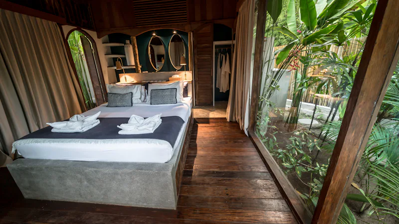 Premium resort bedroom with floor to ceiling windows onto foliage