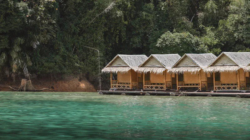 Row of thatched bungalows on the edge of calm green water